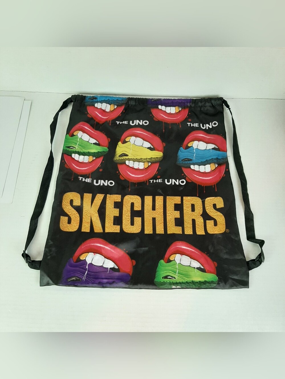 Skechers "The Uno" drawstring backpack featuring a colorful lips graphic print